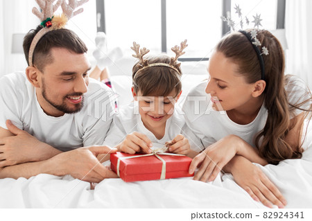 family with christmas gift in bed in morning family with christmas gift in bed in morning 82924341