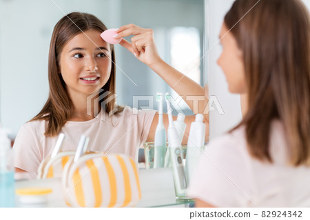 teenage girl applying foundation to face teenage girl applying foundation to face 82924342