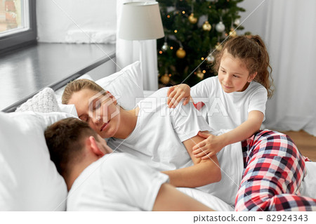 happy girl wakes her parents in christmas morning 82924343