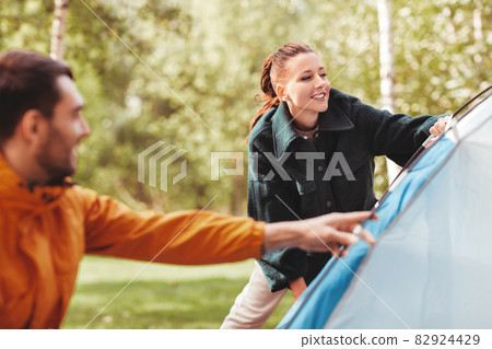 happy couple setting up tent outdoors 82924429