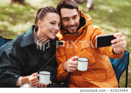 couple drinking tea and taking selfie at tent camp couple drinking tea and taking selfie at tent camp 82924469