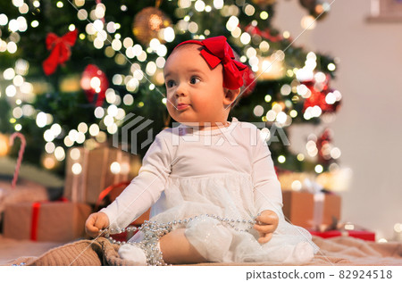 baby girl at christmas tree with gifts at home 82924518