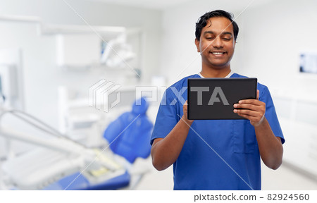 smiling doctor using tablet pc at dental office 82924560