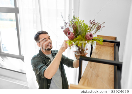 man decorating home with flowers in vase 82924659
