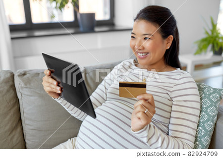 pregnant woman with tablet pc and credit card 82924709
