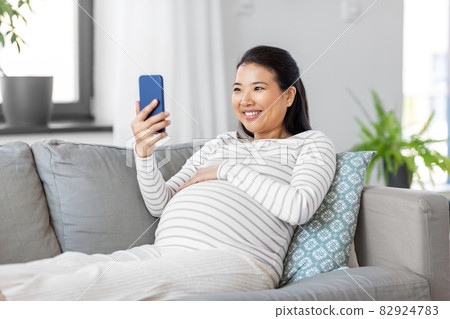 happy pregnant woman with smartphone at home 82924783