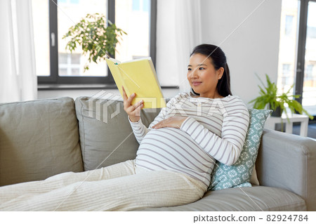 happy pregnant woman reading book at home happy pregnant woman reading book at home 82924784