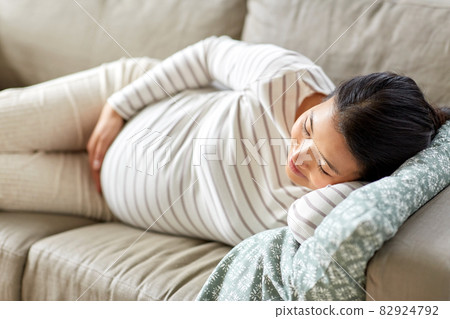 pregnant asian woman sleeping on sofa at home pregnant asian woman sleeping on sofa at home 82924792