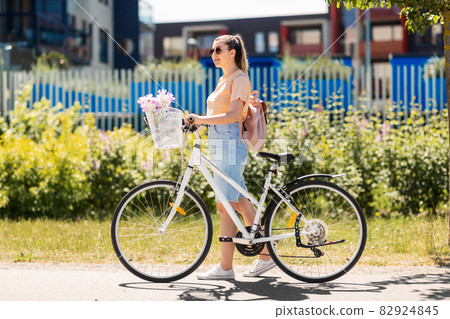 woman with flowers in bicycle basket in city 82924845