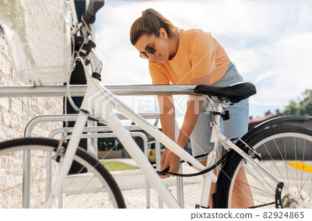 woman parking her bicycle on city street woman parking her bicycle on city street 82924865