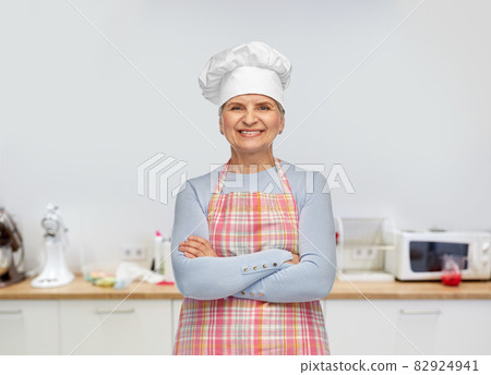 smiling senior woman or chef in toque in apron 82924941
