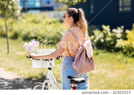woman with flowers in bicycle basket in city woman with flowers in bicycle basket in city 82925037