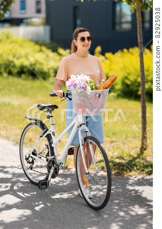 woman with food and flowers in bicycle basket woman with food and flowers in bicycle basket 82925038