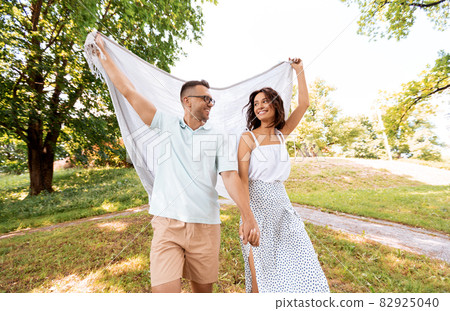 happy couple with picnic blanket at summer park happy couple with picnic blanket at summer park 82925040