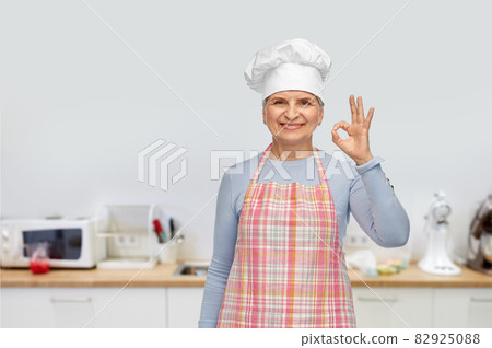 senior woman or chef in toque showing ok hand sign senior woman or chef in toque showing ok hand sign 82925088