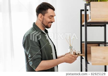 man placing aroma reed diffuser to shelf home man placing aroma reed diffuser to shelf home 82925129