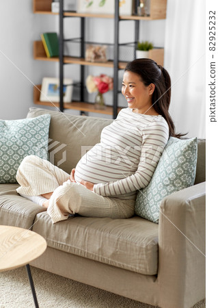 happy pregnant asian woman sitting on sofa at home 82925232