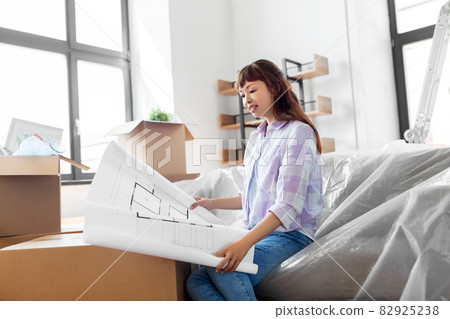 woman with blueprint and boxes moving to new home woman with blueprint and boxes moving to new home 82925238