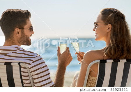 happy couple drinking champagne on summer beach happy couple drinking champagne on summer beach 82925321