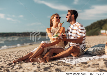 happy couple with food having picnic on beach 82925334