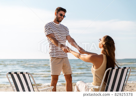 happy couple sitting in folding chairs on beach happy couple sitting in folding chairs on beach 82925378