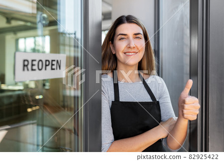 woman with reopen banner on door showing thumbs up woman with reopen banner on door showing thumbs up 82925422