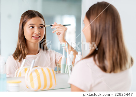 teenage girl applying eye shadow at bathroom 82925447