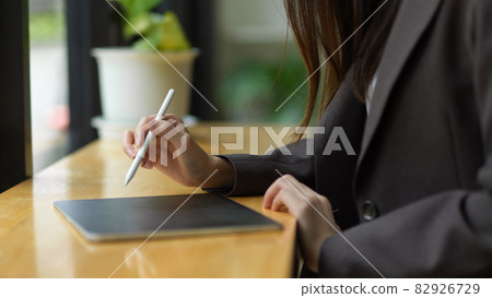 a beautiful businesswoman in a black suit taking notes on a digital tablet a beautiful businesswoman in a black suit taking notes on a digital tablet 82926729