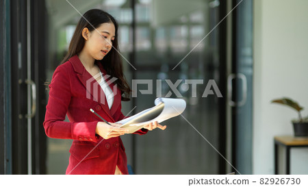 Young millennial asian female entrepreneur reading paperwork documents. 82926730