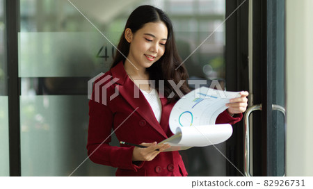 Satisfied business professional woman examines financial report papers Satisfied business professional woman examines financial report papers 82926731