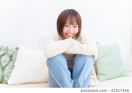 一個女人微笑著坐著，抱著她的膝蓋 82927848