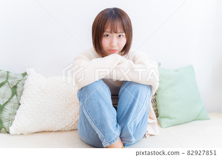 A woman holding her knees and staring at me A woman holding her knees and staring at me 82927851