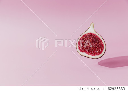 Fresh tasty fig fruit halve levitation with shadow on pink background. Cross section of fig falling down or fly. Vegan desert concept. Shadow of flying healthy eating food. High quality colorful photo Fresh tasty fig fruit halve levitation with shadow on pink background. Cross section of fig falling down or fly. Vegan desert concept. Shadow of flying healthy eating food. High quality colorful photo 82927883
