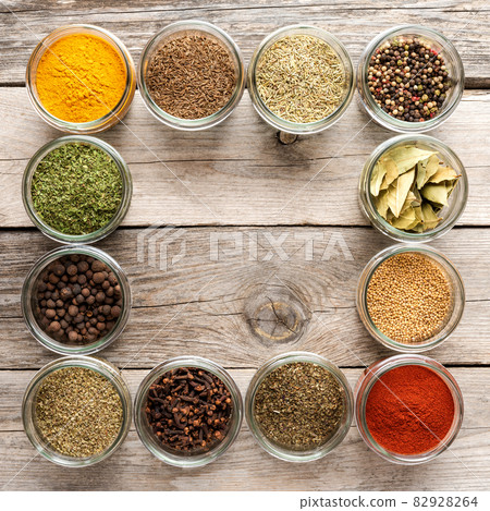 Various types of seasonings in bowls. Collection of seasonings on wooden background  with copyspace 82928264