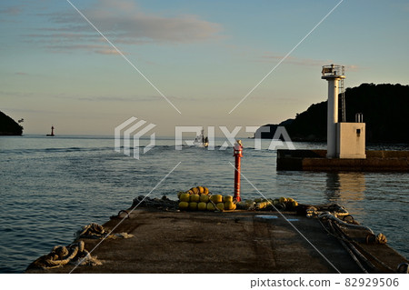 Okinoshima-cho, Oki-gun, Shimane Prefecture Saigo Port and Okinoshima-cho Fishing Port Okinoumi Sea Pier and white lighthouse illuminated by the setting sun 82929506