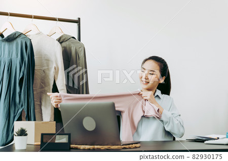 Young asian entrepreneurs are picking up shirts to compare proportions for customers to view them online. Young asian entrepreneurs are picking up shirts to compare proportions for customers to view them online. 82930175