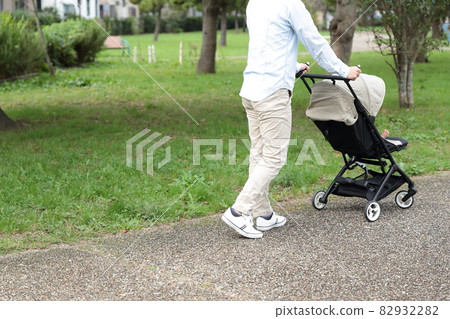 Daddy taking a walk with a 0 year old baby in a stroller 82932282