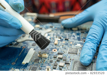 Technician use brush and air blower ball to clean dust in circuit board computer. Repair upgrade and maintenance technology. Technician use brush and air blower ball to clean dust in circuit board computer. Repair upgrade and maintenance technology. 82933520