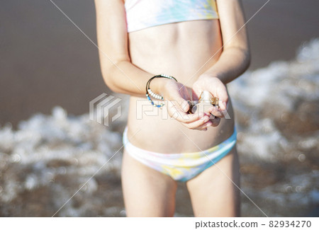 Little girl playing on the beach by the sea Little girl playing on the beach by the sea 82934270