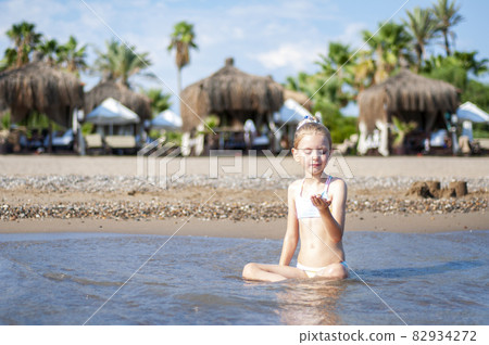 Little girl playing on the beach by the sea Little girl playing on the beach by the sea 82934272