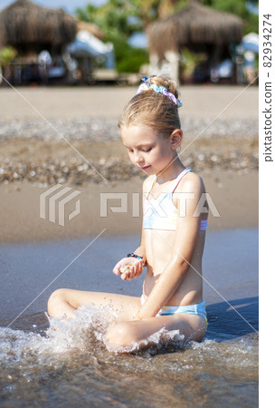 Little girl playing on the beach by the sea Little girl playing on the beach by the sea 82934274