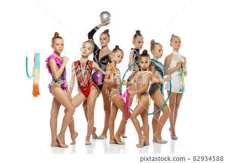 Studio shot of group of mixed-ages beautiful rhythmic gymnastics artists, girls posing isolated on white studio background. Studio shot of group of mixed-ages beautiful rhythmic gymnastics artists, girls posing isolated on white studio background. 82934588