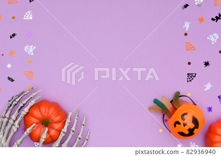 Halloween background with skeleton hands hold a pumpkin and candy bucket. Halloween background with skeleton hands hold a pumpkin and candy bucket. 82936940