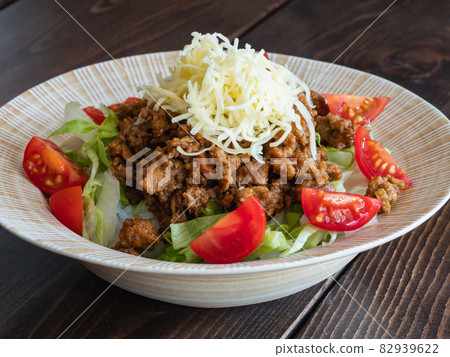 沖繩塔可飯。一盤辛辣的碎肉、生菜、番茄和奶酪,上面放著米飯。 沖繩塔可飯。一盤辛辣的碎肉、生菜、番茄和奶酪,上面放著米飯。 82939622