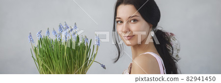 Woman Holding Bouquet of Flowers in Hands Indoors 82941450