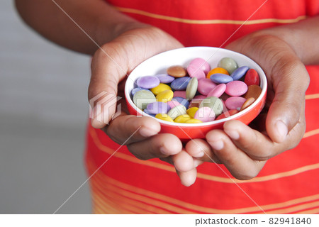 child boy picking multi-colored sweet candies in a bowl close up  82941840
