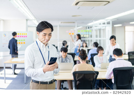 A businessman looking at a smartphone in the office A businessman looking at a smartphone in the office 82942920