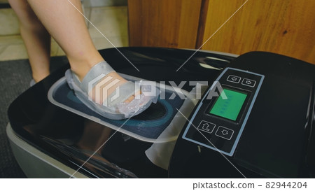 Automatic Thermal Shrinkable Shoe Cover Laminating Machine. Close up. Machine automatically applies shoe covers to the patient shoes. 82944204