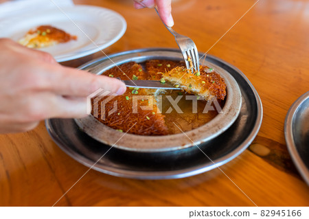 Turkish dessert kunefe, kunafa, kadayif with pistachio powder and cheese, served hot, very sweet. Turkish dessert kunefe, kunafa, kadayif with pistachio powder and cheese, served hot, very sweet. 82945166