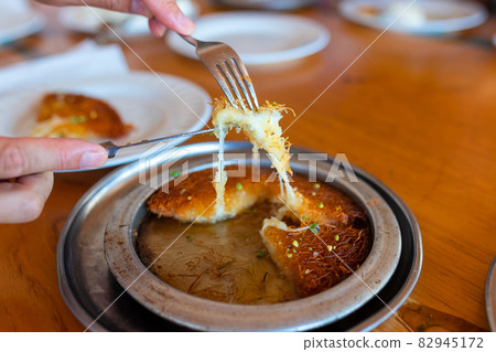 Turkish dessert kunefe, kunafa, kadayif with pistachio powder and cheese, served hot, very sweet. Turkish dessert kunefe, kunafa, kadayif with pistachio powder and cheese, served hot, very sweet. 82945172